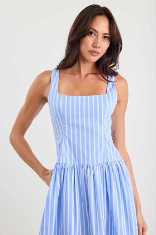 Woman wearing a blue and white striped dress against a plain background