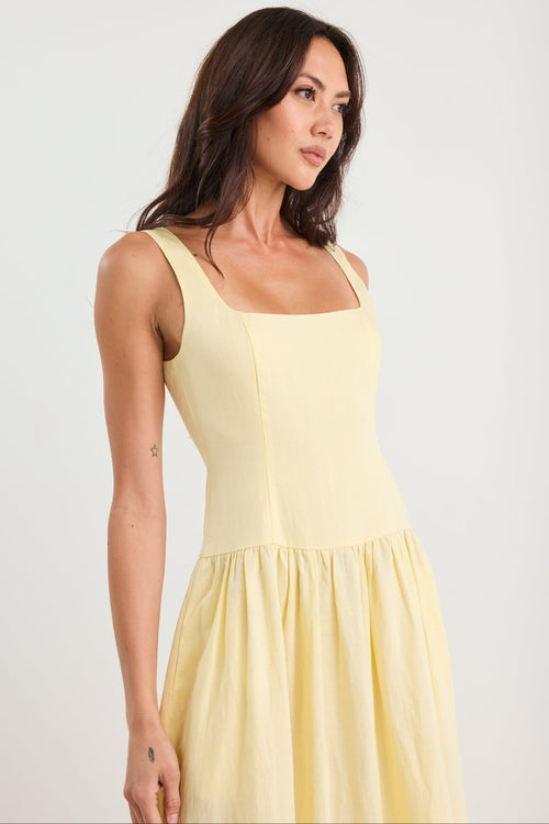Woman wearing a yellow dress against a plain background