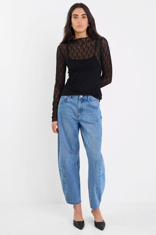 Woman wearing a black lace top and blue jeans on a white background