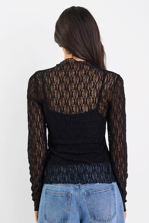 Person wearing a black lace top and blue jeans on a white background