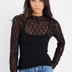 Woman wearing a black lace top and blue jeans on a white background