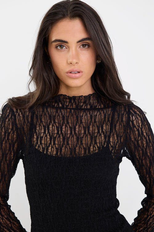 Woman wearing a black lace top against a white background