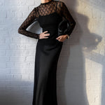 Woman wearing a black dress against a white brick wall