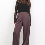 Woman wearing a black top and brown pants on a white background