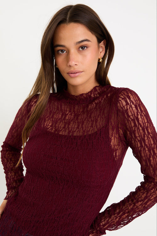 Woman wearing a burgundy lace top against a white background
col_pattern