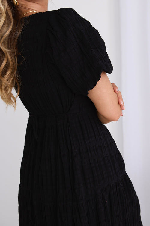 model wears a black midi dress