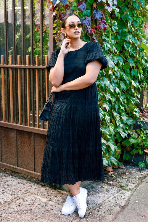 model wears a black midi dress
