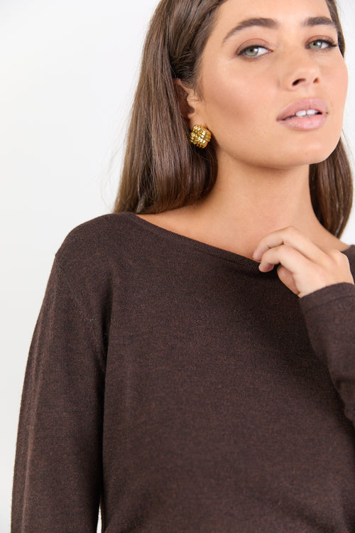Woman wearing a brown sweater with a plain background