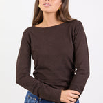 Woman wearing a brown long-sleeve top and blue jeans on a white background