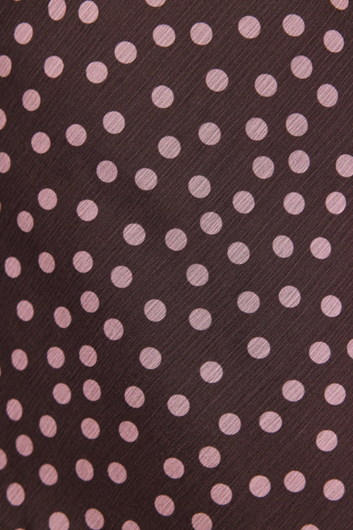 Patterned fabric with pink polka dots on a brown background