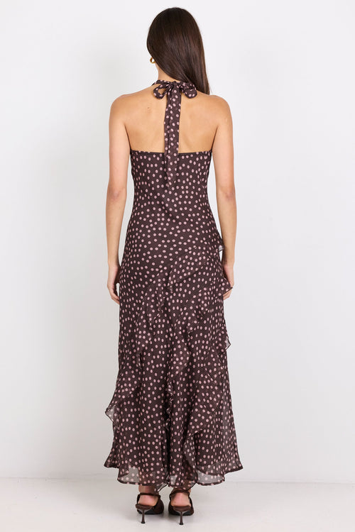 Woman wearing a brown halter maxi dress with pink polka dots on a white background.
