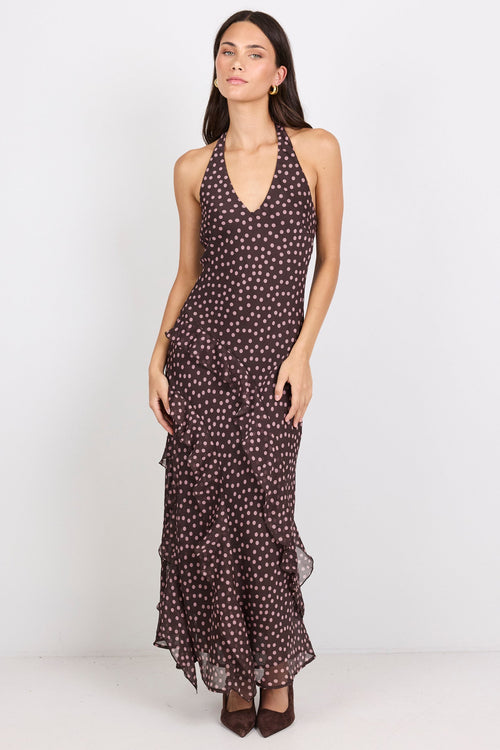 Woman wearing a brown halter maxi dress with pink polka dots on a white background.