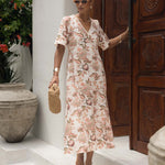 Woman in a floral dress standing in front of a wooden door with decorative carvings.