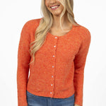 Woman wearing an orange knitted cardigan and blue jeans on a white background
