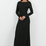 A woman wearing a long-sleeve black textured maxi dress with a fitted silhouette.