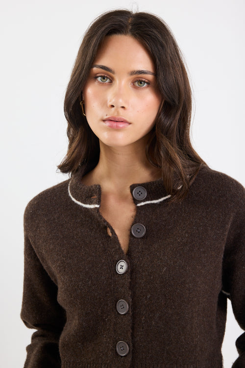 Woman wearing a brown button-up cardigan against a white background