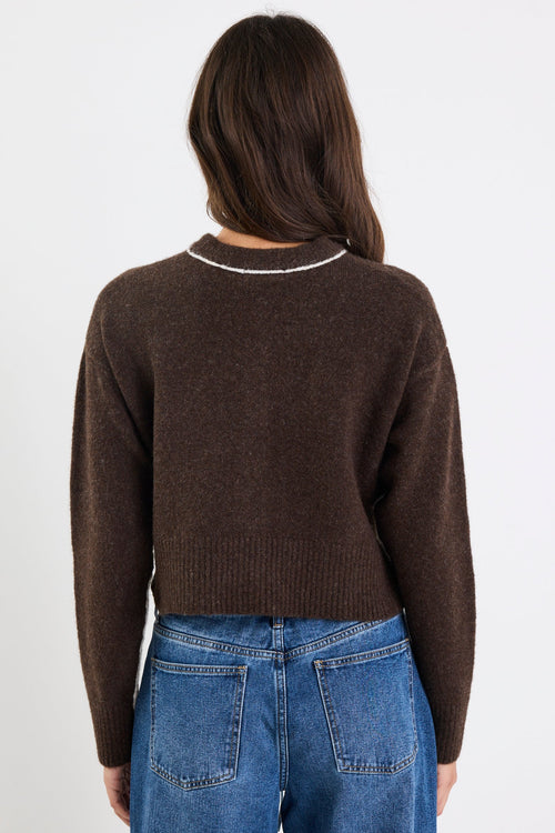Person wearing a brown sweater and blue jeans on a white background