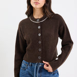 Woman wearing a brown cardigan and blue jeans on a white background