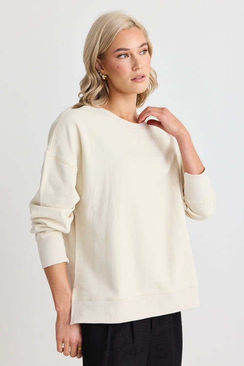 Model wears a cream sweatshirt and black shorts