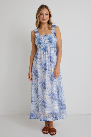 model wears blue floral maxi dress and brown sandals