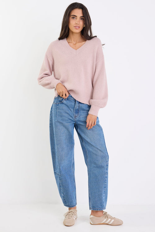 Woman wearing a pink sweater and blue jeans on a white background