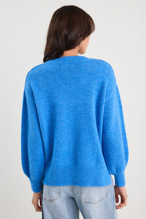 Person wearing a blue sweater and light blue jeans on a plain background