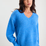 Woman wearing a blue sweater against a plain background