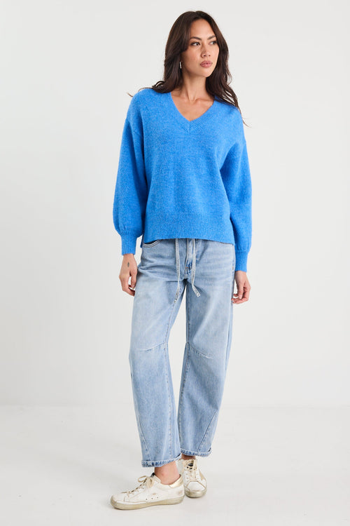 Woman wearing a blue sweater and light blue jeans on a white background