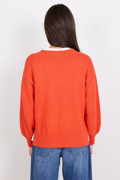 Person wearing an orange sweater and blue jeans on a white background