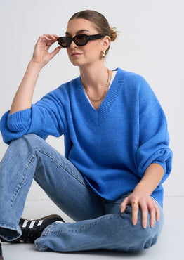 Model wears a blue jumper with jeans