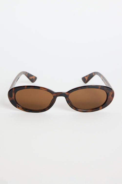 Slim oval tortoiseshell sunglasses with warm brown tinted lenses, photographed on a white background