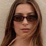 Woman wearing sunglasses against a plain background