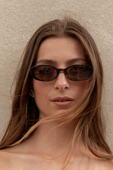Woman wearing sunglasses against a plain background