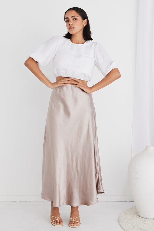 model in white crop top and beige satin maxi skirt and heels