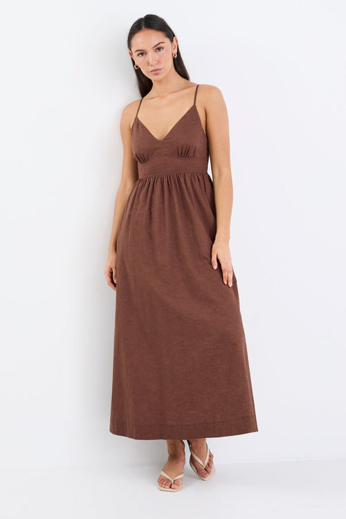 Model wearing a chocolate brown strappy midi dress with a relaxed fit and natural linen-cotton blend.