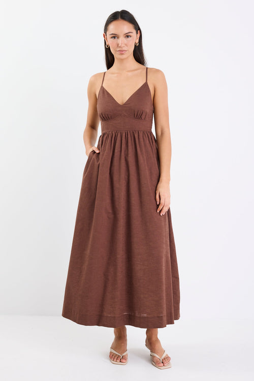 Model wearing a chocolate brown strappy midi dress with a relaxed fit and natural linen-cotton blend.