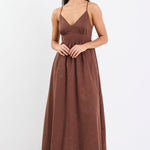 Model wearing a chocolate brown strappy midi dress with a relaxed fit and natural linen-cotton blend.