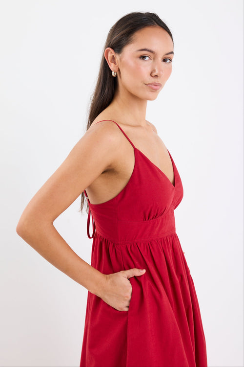 Model wearing a plum strappy midi dress, featuring a relaxed fit and linen-cotton blend fabric with a smooth, polished finish.