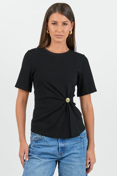 Woman wearing a black top with a gold button and blue jeans on a white background