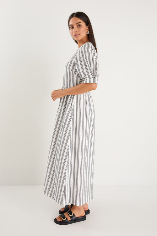 The model wears a white with black stripe detail and black sandals