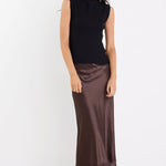 Woman wearing a black sleeveless top and brown skirt on a white background