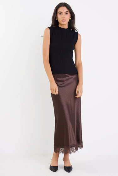 Woman wearing a black sleeveless top and brown skirt on a white background