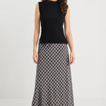 Woman wearing a black sleeveless top and patterned skirt on a white background