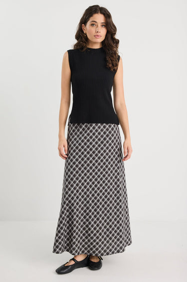 Woman wearing a black sleeveless top and patterned skirt on a white background
