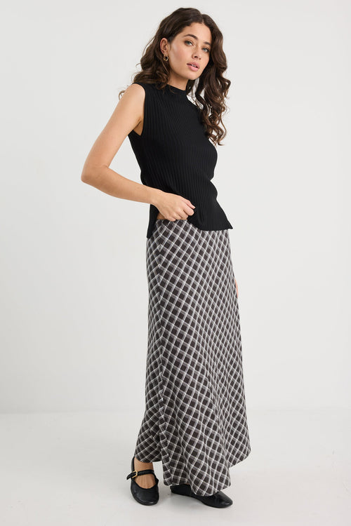Woman wearing a black sleeveless top and checkered skirt on a white background