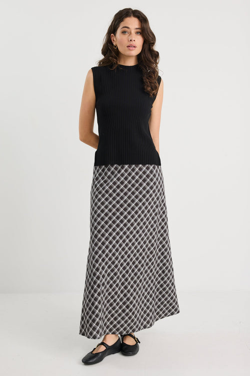 Woman wearing a black sleeveless top and patterned skirt on a white background