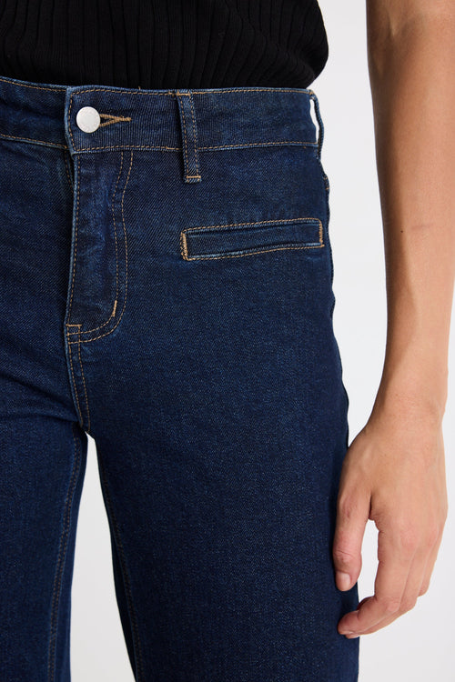 Dark blue jeans worn by a person on a white background