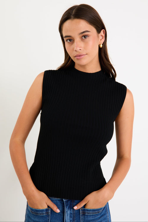 Woman wearing a black sleeveless ribbed top against a white background