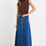 Woman wearing a brown sleeveless top and blue denim skirt on a white background