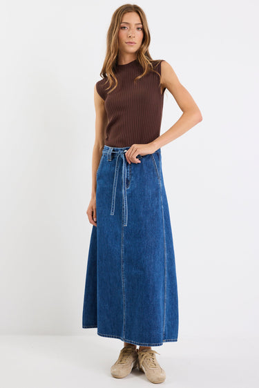Woman wearing a brown sleeveless top and blue denim skirt on a white background